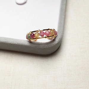 Macro detail of handmade 14K gold-filled wire wrapped ring with colorful tourmaline beads