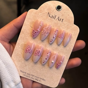 Vue macro d'ongles amande avec cœurs léopard roses et détails de nœuds en 3D
