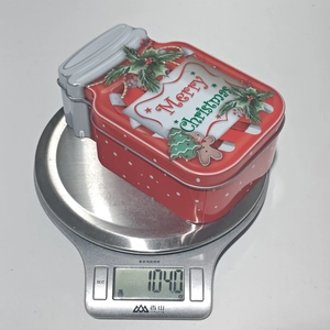 Christmas red tin box shaped like a jar weighing 104.0g on a digital scale