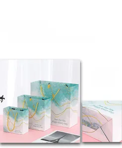 Detailed view of pink and blue watercolor paper gift bags with golden rope handles