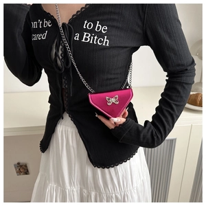 Detail of a magenta triangular mini bag with silver chain and metal butterfly buckle