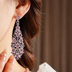 Modelo con elegantes pendientes de plata y cristales morados con diseño de lágrima calada