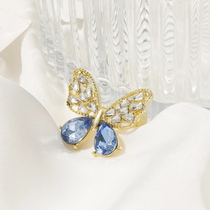 Exquisite hollow butterfly brooch with blue pear-shaped crystals on white silk