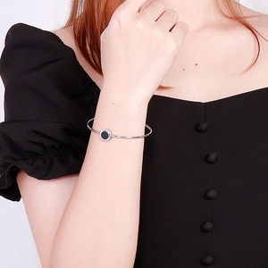 Silver resin open bangle with engraved circular charm shown on a female model wrist