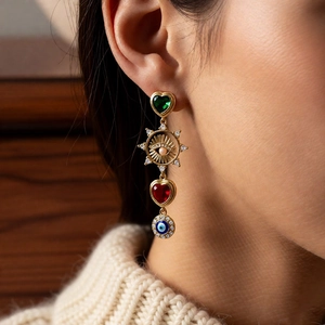 Detail of vintage bohemian drop earrings featuring green heart and evil eye charms