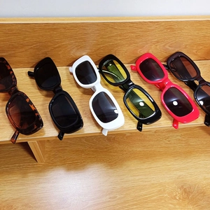 Detailed display of six colorful vintage narrow rectangular sunglasses on wooden stand