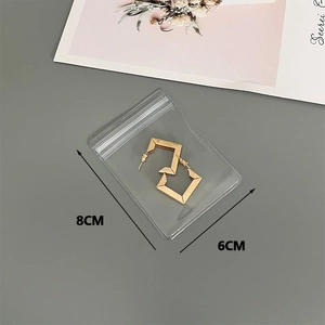 Close-up of golden geometric earrings in 8x6cm transparent PVC self-sealing jewelry pouch