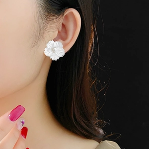 Gros plan de boucles d'oreilles fleur en nacre avec perle centrale sur un mannequin