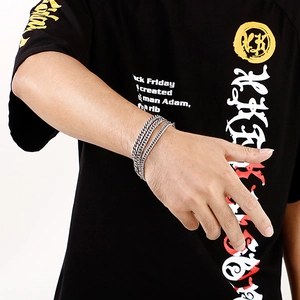 Detailansicht des silbernen drelagigen Panzerarmbandes am Handgelenk eines Männermodels