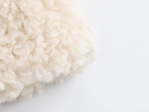 Macro detail of soft white faux fur texture showing curly lamb wool effect fabric