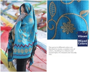 Detail of ethnic blue cashmere shawl with gold floral patterns and black fringe tassels