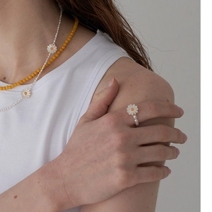 Minimalist pearl daisy ring and beaded necklace set displayed on a fashion model