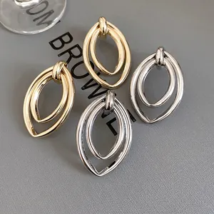 Boucles d'oreilles ovales évidées en or et argent sur un fond sombre élégant