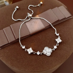 Detail of silver clover bracelet with zircon stones displayed on a brown gift box