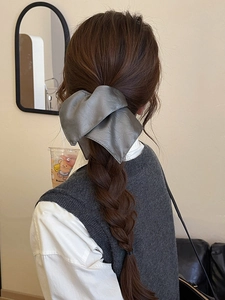 Macro detail of a large grey matte bow hair tie styled on a ponytail back view