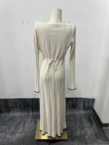 Détail de la robe en maille crème avec bordures noires contrastées et col rond élégant