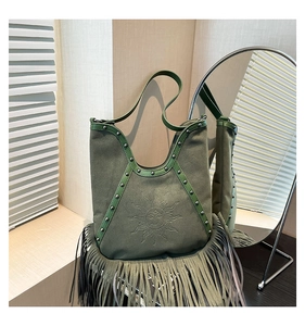 Close-up of bohemian green suede shoulder bag featuring sun relief and long fringe tassels
