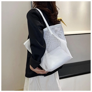 Side view of a white mesh tote bag held by a model in a stylish black and white outfit