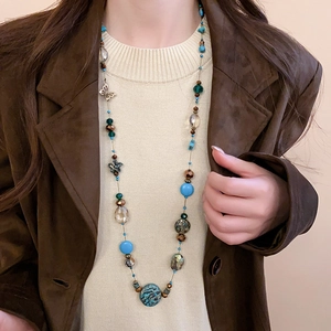 Detail of bohemian layered beaded necklace featuring butterfly accents and turquoise tones