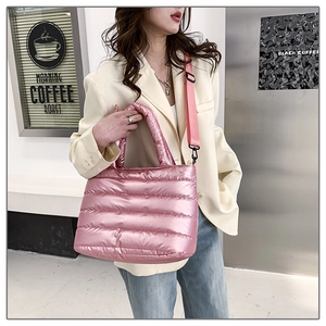 Pink quilted down tote bag with metallic finish shown with crossbody strap in outdoor setting