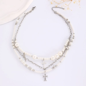Detail of layered necklace featuring faux pearls, metal chains, and cross pendants