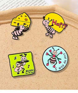 Detailed view of four cute enamel ant badges on a beige tray with decorative newspaper background