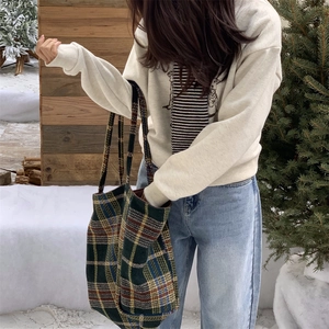 Détail d'un grand sac cabas en laine à carreaux dans un décor d'hiver avec neige