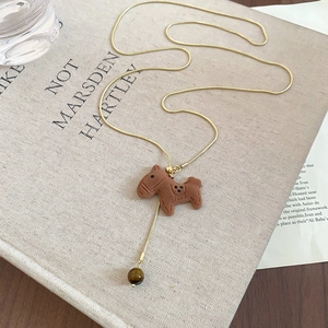 Macro view of gold snake chain with brown pony pendant and tiger eye bead detail