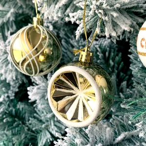 Detail of golden Christmas ball with white flocking patterns on a snowy tree branch