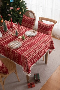 Detail of red and beige Christmas tablecloth with elk patterns and elegant fringed edges