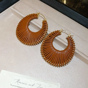 Détail de boucles d'oreilles géométriques dorées présentées dans un écrin à bijoux beige