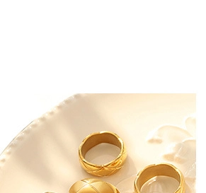 Makroaufnahme von goldenen Ringen mit Rautenmuster auf weißem Keramikteller
