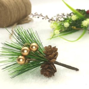 Christmas pine branch pick with gold berries and pine cones on plush white background