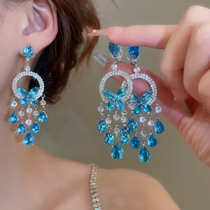 Macro shot of silver tassel earrings with blue zircon butterfly and water drop pendants