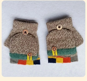 Detailansicht der Strickhandschuhe mit gestreiften Bündchen und dekorativem Holzknopf