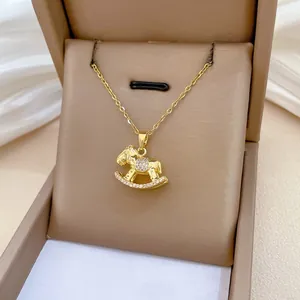 Detailed view of a golden rocking horse pendant necklace with crystals in a jewelry box