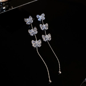 Détail macro de boucles d'oreilles pampilles en argent avec papillons en zircon brillant