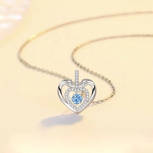 Macro shot of silver heart pendant with sky blue gemstone and white zircon stones