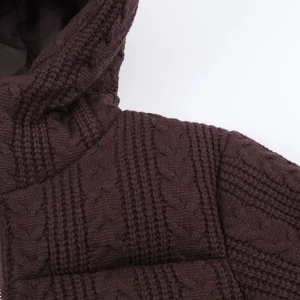 Dettaglio della trama in maglia intrecciata marrone scuro su cappotto con cappuccio