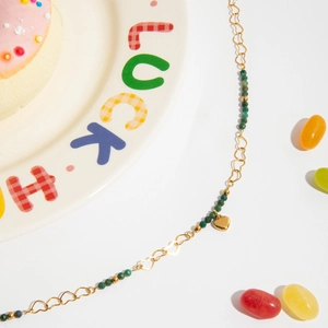 Gold-plated necklace with green natural stone and hollow heart pendant on white plate