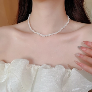 Detailed view of elegant multi-strand woven pearl necklace on model's neck and collarbone