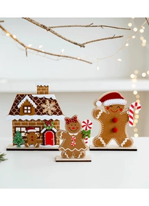 Close-up of felt gingerbread man and house Christmas tabletop decorations with warm bokeh lights