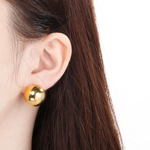 Close-up of elegant gold hollow sphere earrings worn by a model in a bright setting