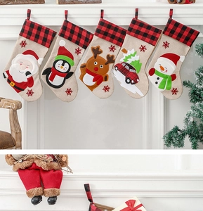 Five linen Christmas stockings with red buffalo plaid cuffs hanging on a white fireplace