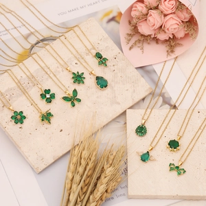 Golden necklaces with emerald cubic zirconia charms in butterfly and flower shapes