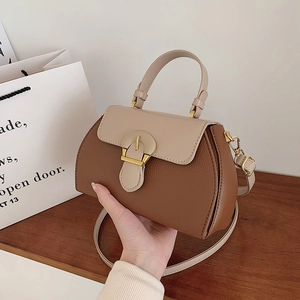 Detail of lychee pattern leather contrast color handbag with gold circular clasp closure