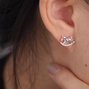 Macro shot of silver rocking horse stud earring with sparkling textured finish on ear
