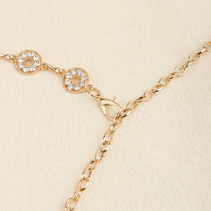 Detailed close-up of golden rhinestone circular links and lobster clasp on waist chain