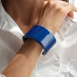 Gros plan sur un bracelet manchette en résine bleu marine avec finition brillante