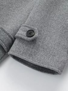 Detailed close-up of grey wool coat cuff featuring a black button and fine stitching